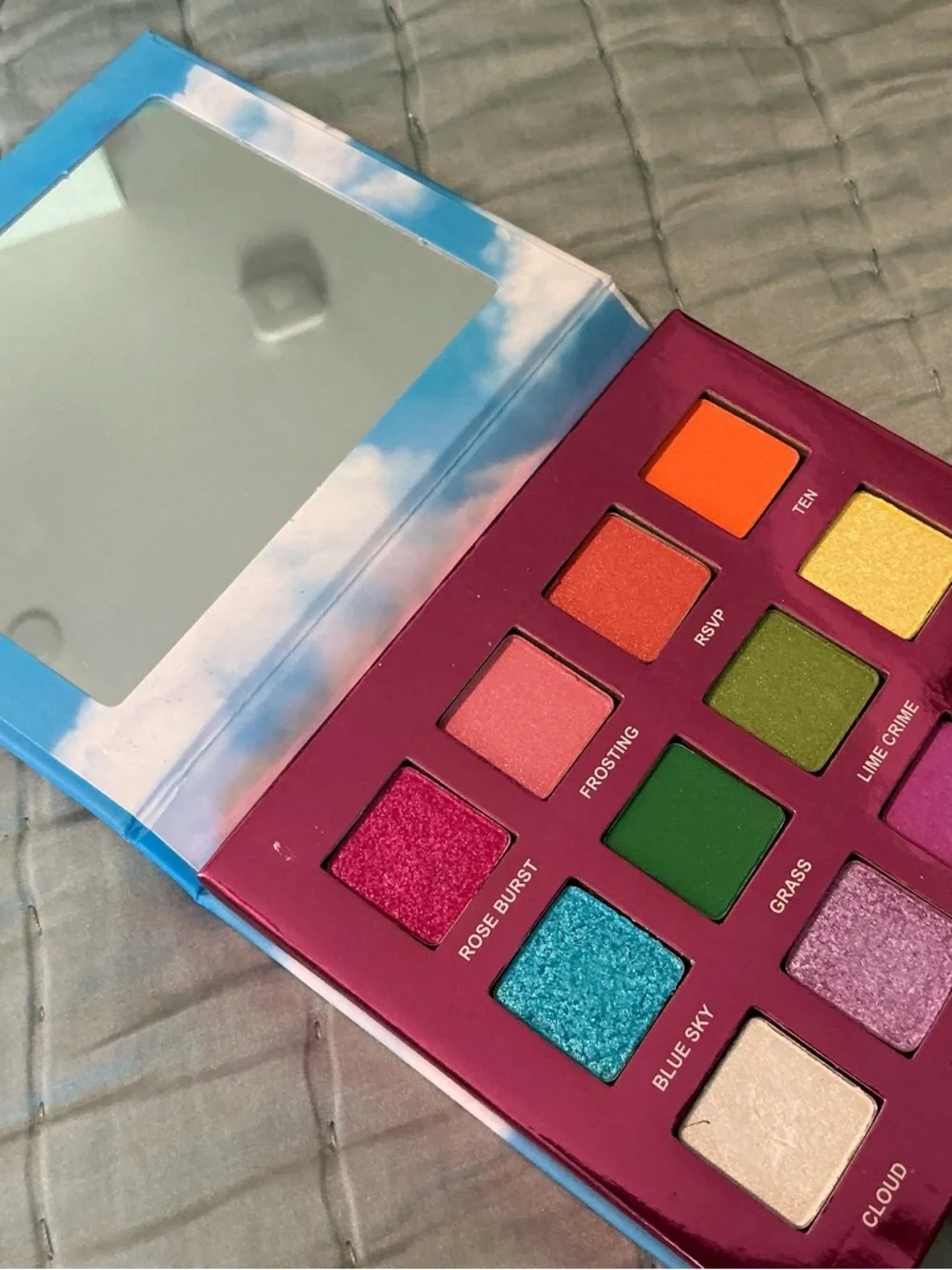 Lime Crime Eyeshadow Palette with Pink Unicorn Logo on Blue Cloud Cover